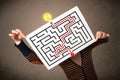 Woman holding a paper with a labyrinth on it in front of her head