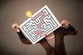 Woman holding a paper with a labyrinth on it in front of her head