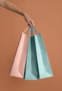 Woman holding paper shopping bags on light brown background, closeup Royalty Free Stock Photo