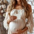 a woman is holding a piece of paper, pregnant belly