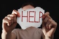 Woman holding piece of paper with word Help on black background, closeup. Domestic violence concept Royalty Free Stock Photo