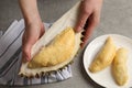 Woman holding piece of ripe durian over grey table, top view