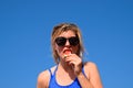 A woman is holding a piece of watermelon near her mouth against the blue sky. A ripe watermelon in the hands of a blonde Royalty Free Stock Photo