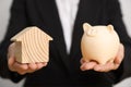 Woman holding piggy bank and house model on white background, closeup Royalty Free Stock Photo