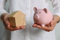 Woman holding piggy bank and house model on white background, closeup Royalty Free Stock Photo