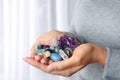 Woman holding pile of different gemstones indoors