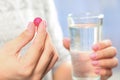 Woman holding pill and glass of water on blurred background, closeup Royalty Free Stock Photo