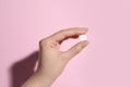 Woman holding pill on pink background, closeup Royalty Free Stock Photo