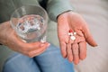 Woman holding pills and glass of water in hands