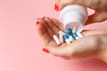 Woman holding pills on hand. Medicine and health care concept. Hand spilling pills for the pain of a bottle on pink background Royalty Free Stock Photo