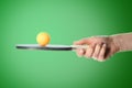 Woman holding ping pong paddle with ball on green background, closeup. Table tennis championship