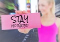 Woman holding placard that reads stay motivated against city Royalty Free Stock Photo