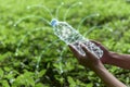 Woman holding plastic bottle glow by polygon design with green tree background.