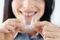 Woman holding plastic mouth guard for bruxism treatment closeup