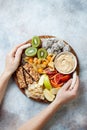 Woman holding plate with healthy vegan sweet dessert snacks - protein granola bars, homemade raw energy balls