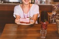 Woman holding plate of slice currant mousse cake in cafe.