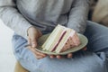 Woman holding a plate of strawberry sponge cake in a cafe, close-up.