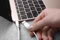 Woman holding plugged USB cable into laptop at grey table, closeup Royalty Free Stock Photo