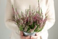 Woman holding pot with heather in her hands. Home gardening, house decoration with seasonal fall plants. Close-up