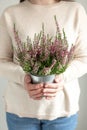 Woman holding pot with heather in her hands. Home gardening, house decoration with seasonal fall plants. Vertical photo