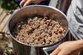 Woman holding a pot of selfmade dog or cat food, meat and innards or mince