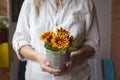 Woman holding potted colorful flowers on balcony