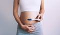 Woman holding pregnancy test in hands near her belly