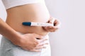 Woman holding pregnancy test in hands near her belly