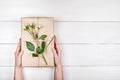 Woman holding present box with rose flowers on wooden table, copy space. Gift in girl`s hands, free space. Holiday background Royalty Free Stock Photo