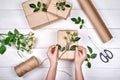 Woman holding present box with roses on white wooden table background, free space. Close up of gift box in girl`s hands Royalty Free Stock Photo