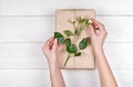 Woman holding present box with roses on white wooden table background, free space. Close up of gift box in girl`s hands Royalty Free Stock Photo