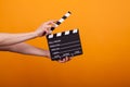 Woman holding professional film slate, movie clapper board in studio over yellow background Royalty Free Stock Photo