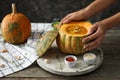Woman holding pumpkin bowl with tasty cream soup on wooden table