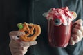 Woman holding pumpkin halloween cookie missing a bite and mug with scary halloween beverage Royalty Free Stock Photo