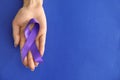 Woman holding purple ribbon on color background. Pancreatic cancer awareness concept