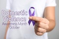 Woman holding purple ribbon on background, closeup. Symbol of Domestic Violence Awareness