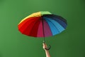 Woman holding rainbow umbrella on color background. LGBT concept