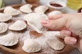 Woman holding raw dumpling varenyk with tasty filling at wooden board, closeup