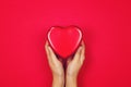 Woman holding red heart in hand on red background with copy space. Flat lay. Top view. Charity Concept.