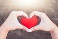 Woman holding red heart and make hand heart shape