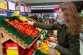 Woman holding red pepper, examining it with care, while grocery shopping in supermarket Royalty Free Stock Photo