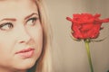 Woman holding red rose near face looking melancholic