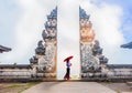 Woman holding red umbrella in temple gates at Lempuyang Luhur temple in Bali, Indonesia