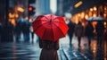 A Woman is holding a red umbrella and walking on a city street. Rainy weather.