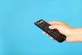 Woman holding remote control on light blue background, closeup. Space for text Royalty Free Stock Photo