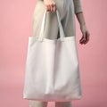 Woman holding reusable white blank tote bag on pink background for mockup