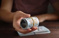 Woman holding rolled dollar banknotes at wooden table, closeup