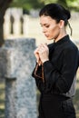 Woman holding rosary beads near tombstone Royalty Free Stock Photo