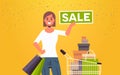 Woman holding sale banner female customer with trolley cart full of gift boxes special offer shopping concept flat