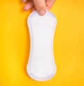 Woman is holding sanitary napkin in hand on yellow Royalty Free Stock Photo